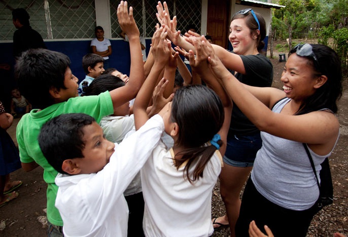 UP students high-five with Nicaraguan children on immersion service project.