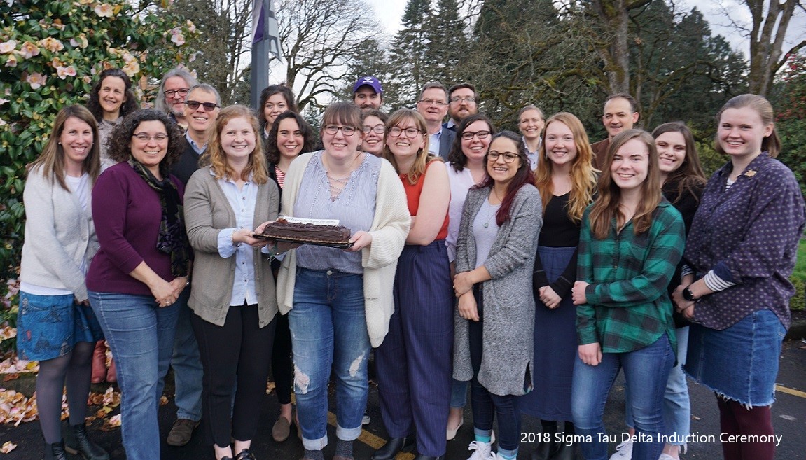 A group of people, one holding a cake, at the 2018 Sigma Tau Delta induction ceremony