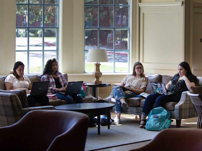 Students in a study space filled with chairs and couches