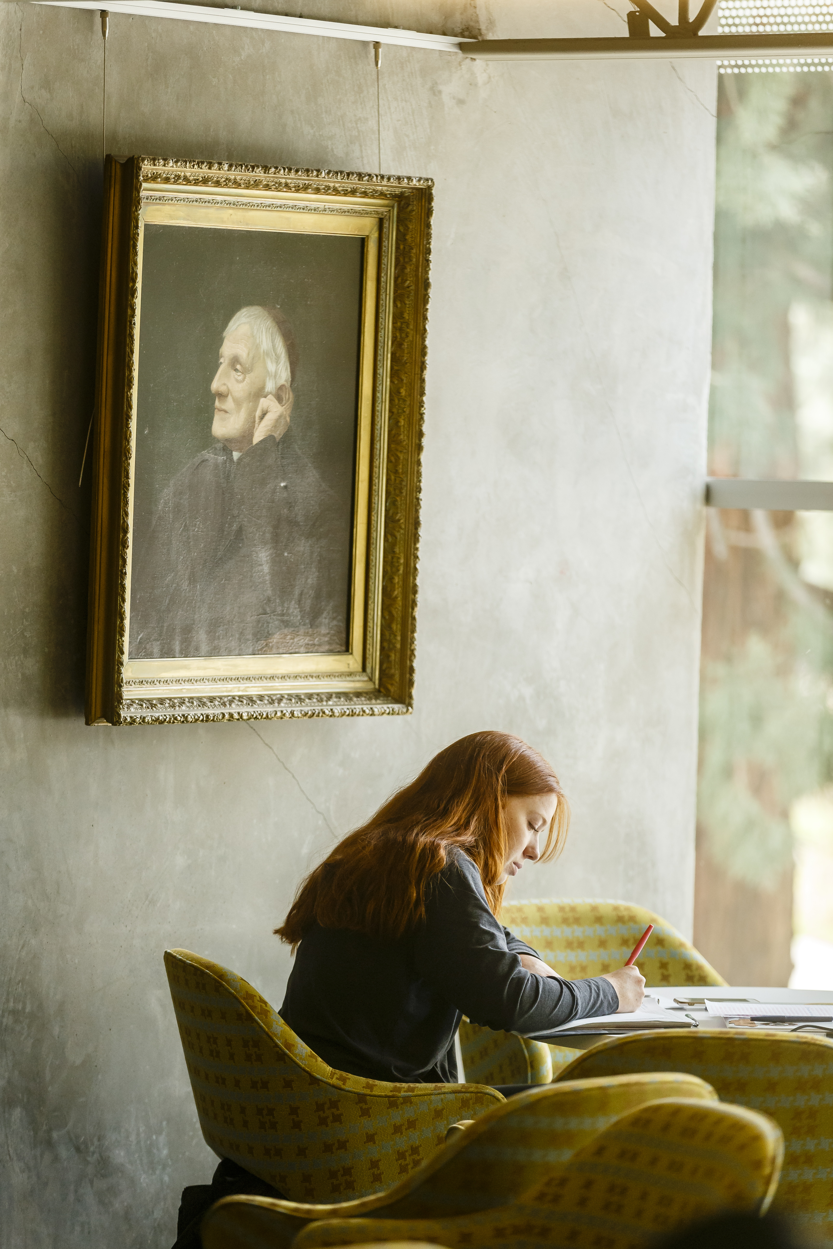 A student studying in the Clark Library under an antique portrait.
