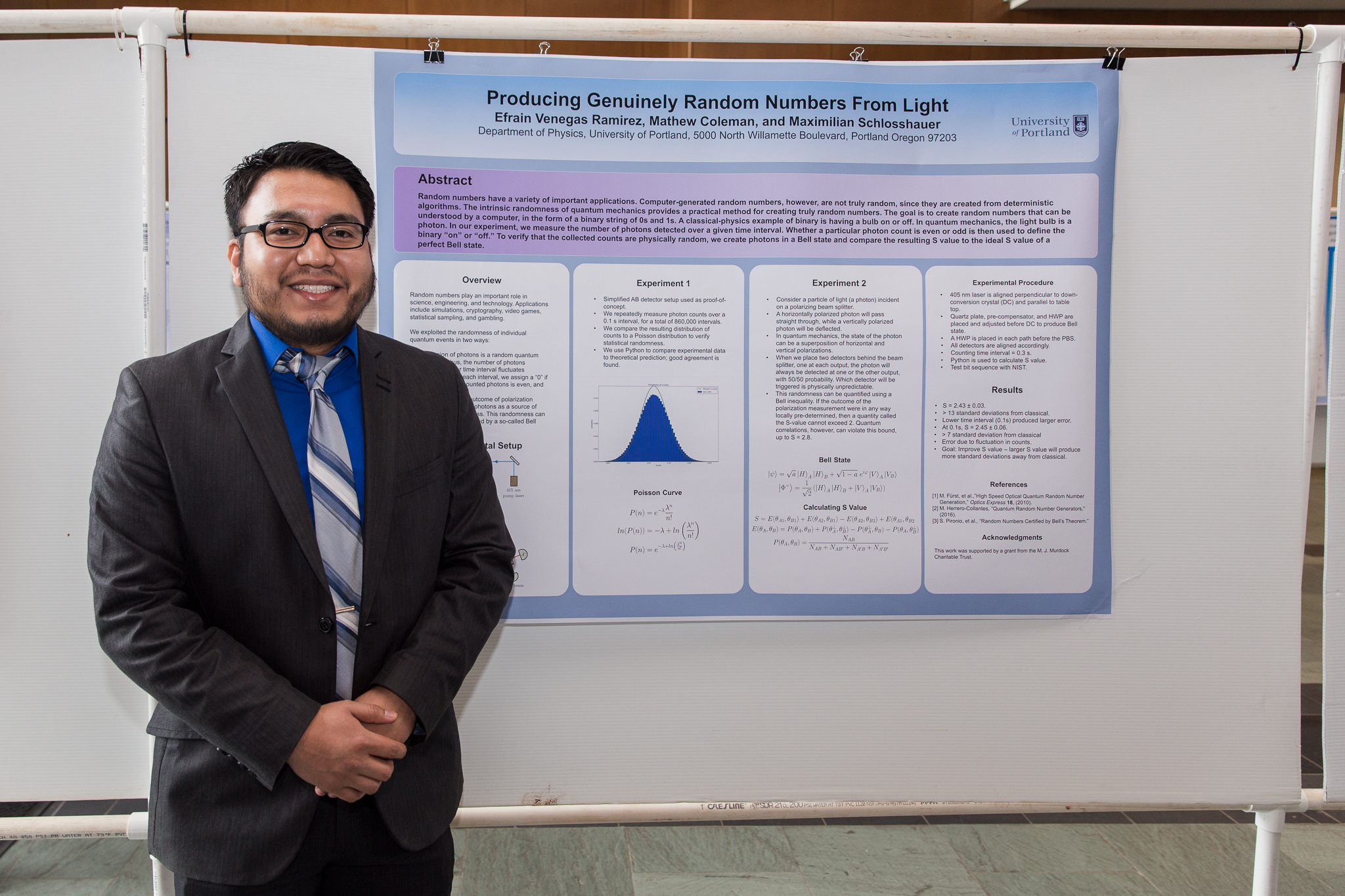 A Physics student stands in front of their Founders' Day poster presentation