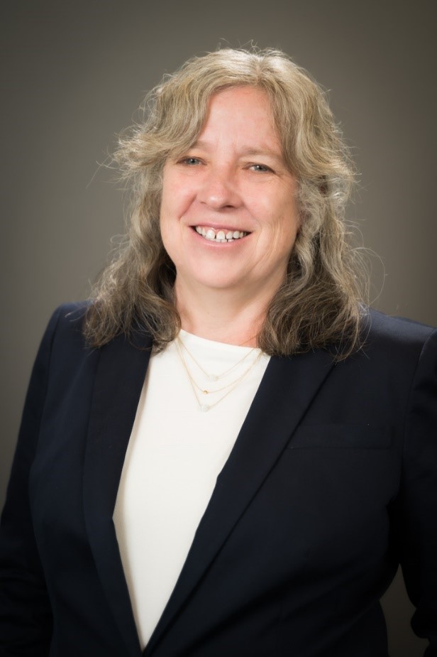 Dean Valerie Banschbach, a blonde woman wearing a black blazer and white shirt, smiling.