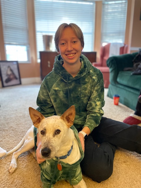 A photo of Laura Stephenson, a young student smiling, posed with a dog