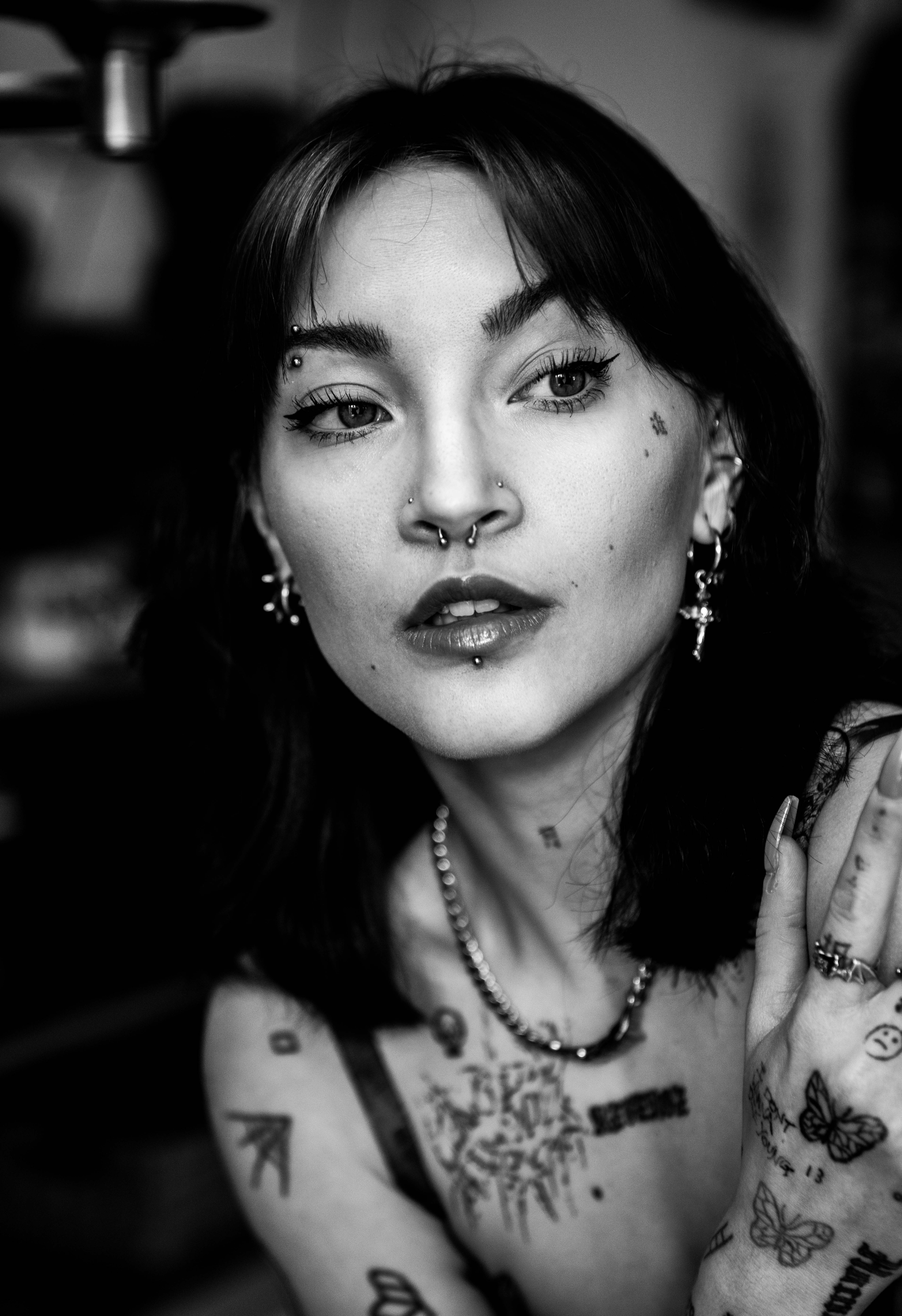 Rebby Yuer Foster, a Chinese-American person with brunette hair, tattoos and piercings. Blac and white photo.